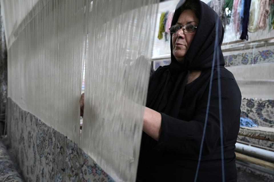 An Iranian woman weaves a carpet at a workshop in the city of Kashan, about 152 miles (245 km) south of the capital Tehran, Iran, Tuesday, April 30, 2024. (AP Photo/Vahid Salemi)