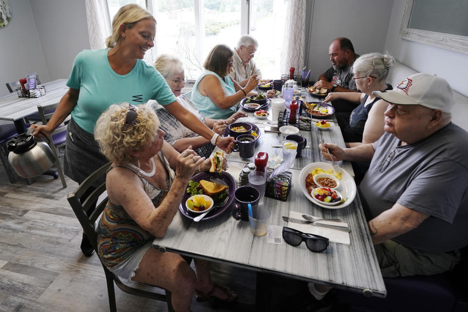 Waitress Kelly Houde, left, fills coffee cups for senior citizens having breakfast as part of the Meals on Wheels "Dine Out Club" at the White Birch Cafe, Wednesday, July 19, 2023, in Goffstown, N.H. Senior participants sign up for the program and swipe credit- and keychain-style cards with QR codes for their allotted meals. (AP Photo/Charles Krupa)