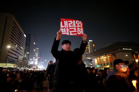 A man holds up a sign that reads "Step down Park Geun-hye" during a protest calling for South Korean President Park Geun-hye to step down in central Seoul, South Korea, December 3, 2016. REUTERS/Kim Hong-Ji - RTSUGDY