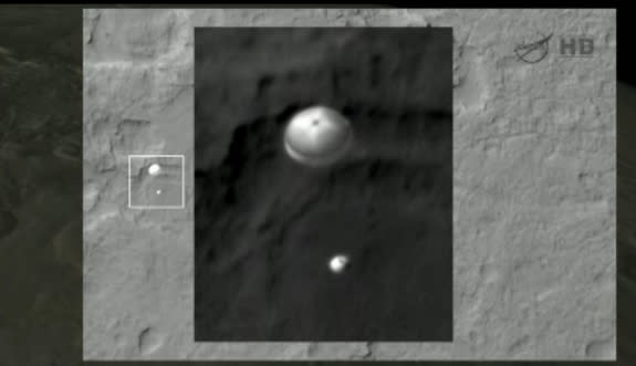 This still from NASA TV shows a photo of the Mars rover Curiosity under its parachute as it landed on Mars on Aug. 5 PDT, 2012. The photo was taken by NASA's Mars Reconnaissance Orbiter. The inset is has been enlarged and adjusted to reduce sat