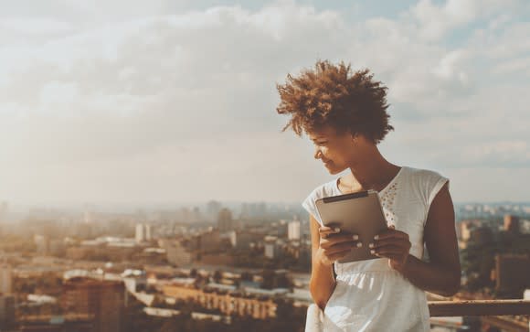 Woman standing with a tablet, overlooking a city