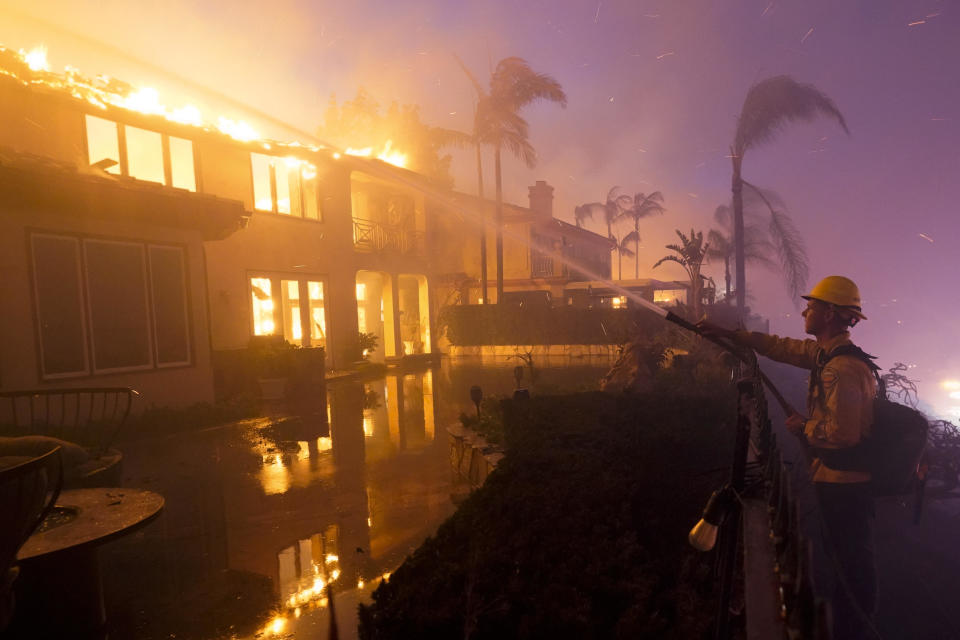 A firefighter works to extinguish flames from a wildfire on May 11, 2022, in Laguna Niguel, Calif. / Credit: Marcio Jose Sanchez / AP