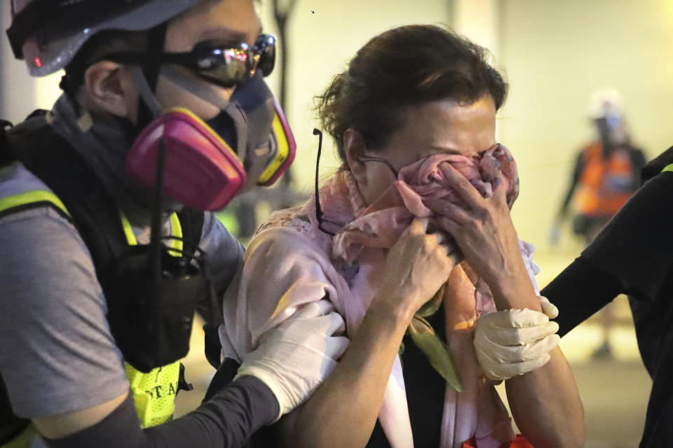 A volunteer medic escorts a woman affected by tear gas during a protest in Hong Kong, Saturday, Nov. 2, 2019. Hong Kong riot police fired multiple rounds of tear gas and used a water cannon Saturday to break up a rally by thousands of masked protesters demanding meaningful autonomy after Beijing indicated it could tighten its grip on the Chinese territory. (AP Photo/Kin Cheung)