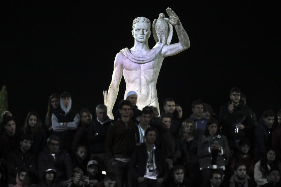 One of the statues by sculptor Eugenio Baroni adorns the Pietrangeli tennis stadium behind spectators watching a match at the Italian Open tennis tournament, in Rome, Thursday, May 16, 2019. The tennis stadium is part of the Foro Italico sports complex, which was initially called Foro Mussolini (Mussolini's Forum). It was built under Benito Mussolini's regime to bolster Rome's bid for the 1944 Olympics, which never took place. (AP Photo/Andrew Medichini)