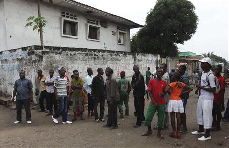 Residents gather to watch as security forces patrol the street near the state television headquarters in the capital Kinshasa, December 30, 2013. REUTERS/Jean Robert N'Kengo