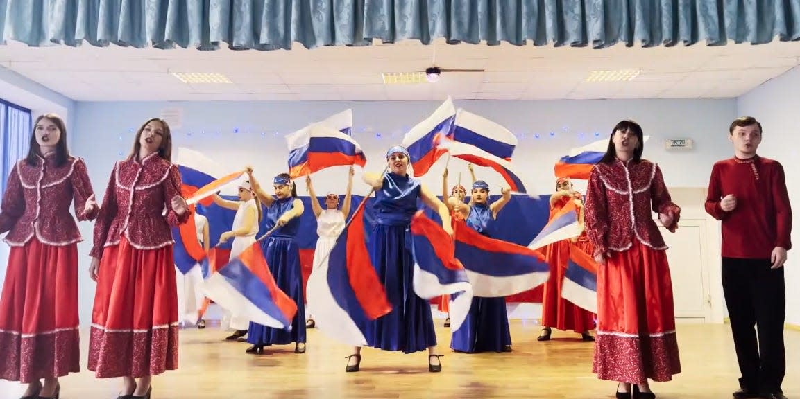A Russian propaganda lesson featuring students dancing with Russian flags.