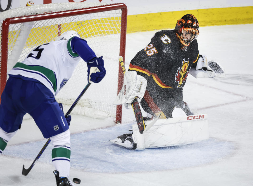 Vancouver Canucks forward Ilya Mikheyev, left, scrambles for a loose puck as Calgary Flames goalie Jacob Markstrom gets caught out of position during the second period of an NHL hockey game, Saturday, Dec. 2, 2023 in Calgary, Alberta. (Jeff McIntosh/The Canadian Press via AP)