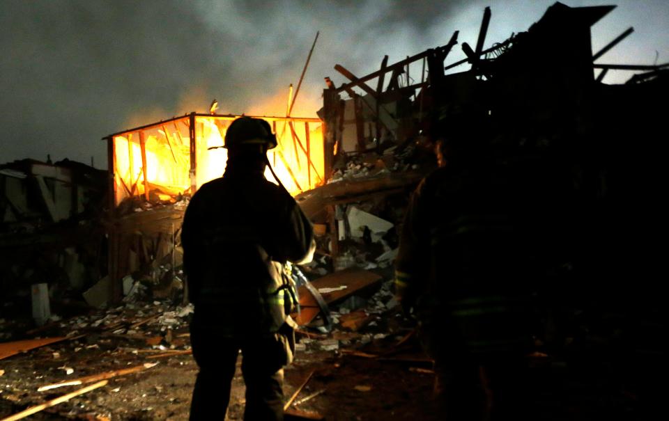 Firefighters search a destroyed apartment complex early in the morning after the explosion in West.