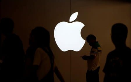 A man looks at the screen of his mobile phone in front of an Apple logo outside its store in Shanghai, China July 30, 2017. REUTERS/Aly Song