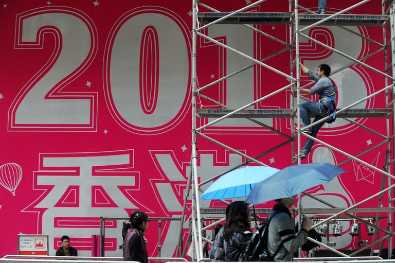 A worker prepares a promotional 2013 banner outside a shopping mall in Hong Kong on Saturday. As the clock strikes 12 on Monday, millions will pop champagne corks and light fireworks while others indulge in quirkier New Year's rituals like melting lead, leaping off chairs or gobbling grapes