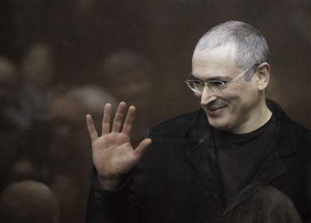 Jailed Russian former oil tycoon Mikhail Khodorkovsky waves as he stands in the defendants' cage before the start of a court session in Moscow in this December 27, 2010 file photograph. REUTERS/Denis Sinyakov/Files