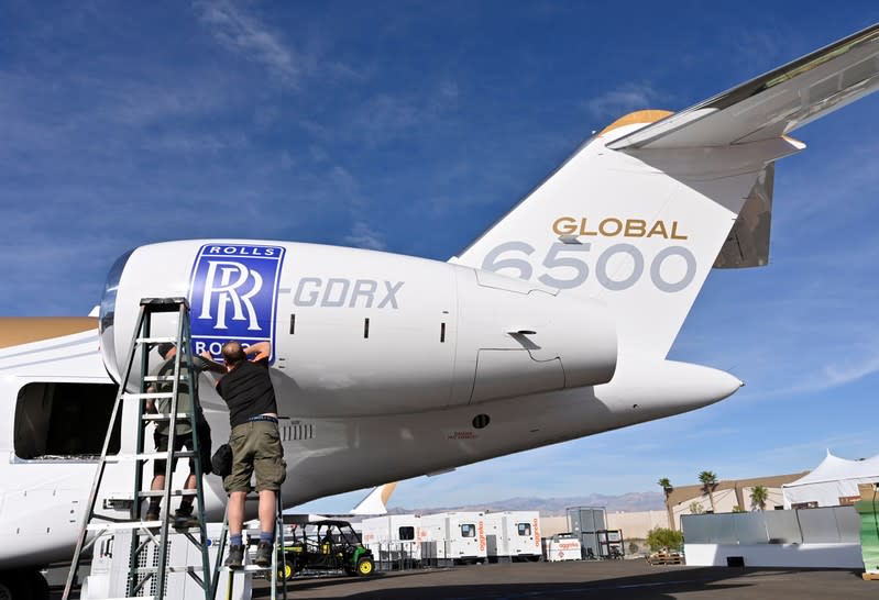 Workers apply a Rolls Royce decal to the engine of a Bombardier Global 6500 business jet at the Bombardier booth at the National Business Aviation Association (NBAA) exhibition in Las Vegas