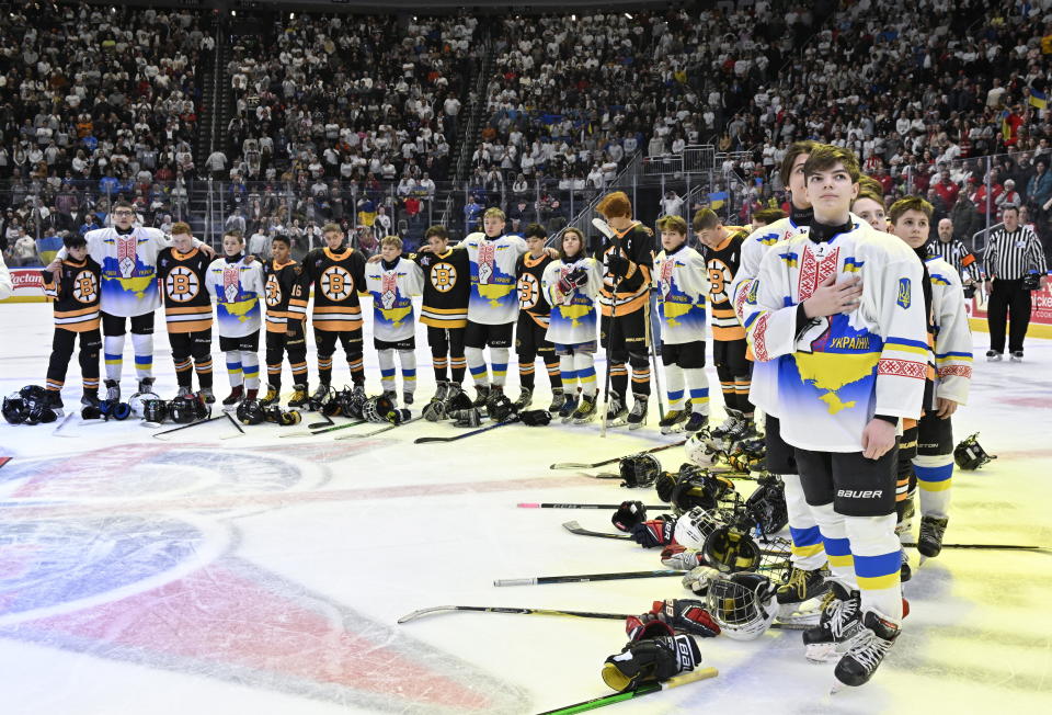 Ukraine and Boston Junior Bruins peewee teams stand together during the national anthems before a hockey game, Saturday, Feb, 11, 2023, in Quebec City. (Jacques Boissinot/The Canadian Press via AP)