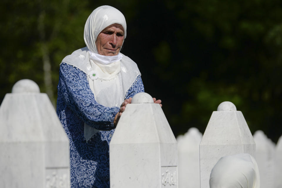 A woman touches a gravestone in Potocari, near Srebrenica, Bosnia, Saturday, July 11, 2020. Nine newly found and identified men and boys were laid to rest as Bosnians commemorate 25 years since more than 8,000 Bosnian Muslims perished in 10 days of slaughter, after Srebrenica was overrun by Bosnian Serb forces during the closing months of the country's 1992-95 fratricidal war, in Europe's worst post-WWII massacre. (AP Photo/Kemal Softic)