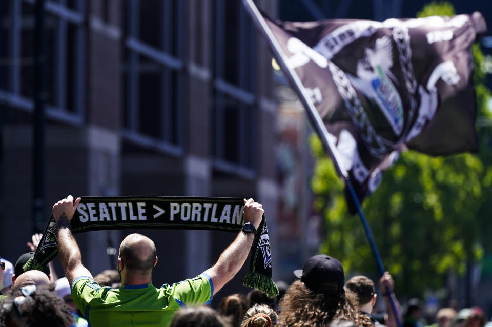 A fan holds a scarf reading "Seattle > Portland" during a march before an MLS soccer match between the Seattle Sounders and the Portland Timbers, Saturday, June 3, 2023, in Seattle. (AP Photo/Lindsey Wasson)