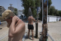 Two men take a shower during a heatwave at a beach, in Alimos suburb, southern Athens, Greece, Monday, Aug. 2, 2021. The heat wave is expected to peak Monday, with temperatures inland ranging from 42 to 46 degrees Celsius (107.6 to 114.8 Fahrenheit). Temperatures will remain at 40 Celsius (104 Fahrenheit) or above in much of Greece until at least Friday, meteorologists say. (AP Photo/Michael Varaklas)