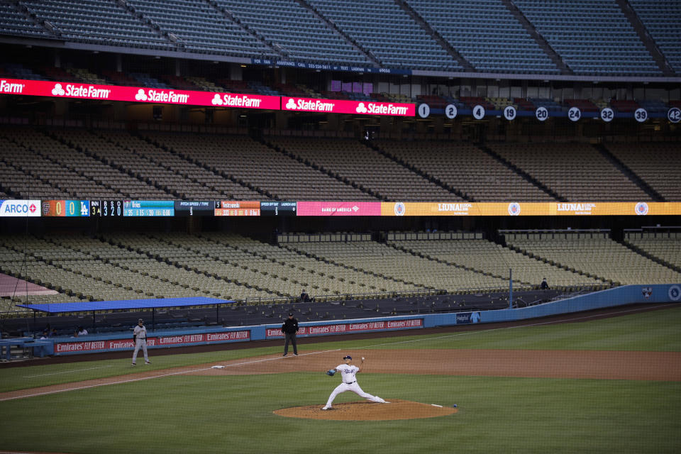 FILE - In this July 26, 2020, file photo, with the seats in Dodger Stadium empty, Los Angeles Dodgers starting pitcher Julio Urias throws the ball to a San Francisco Giants batter during the third inning of a baseball game in Los Angeles. Los Angeles and San Francisco are poised Tuesday, May 4, to be the only major urban areas in the state to meet guidelines to move into the least-restrictive tier. It's a remarkable turnaround considering California was the epicenter of the virus outbreak in the U.S. just a few months earlier. (AP Photo/Jae C. Hong, File)