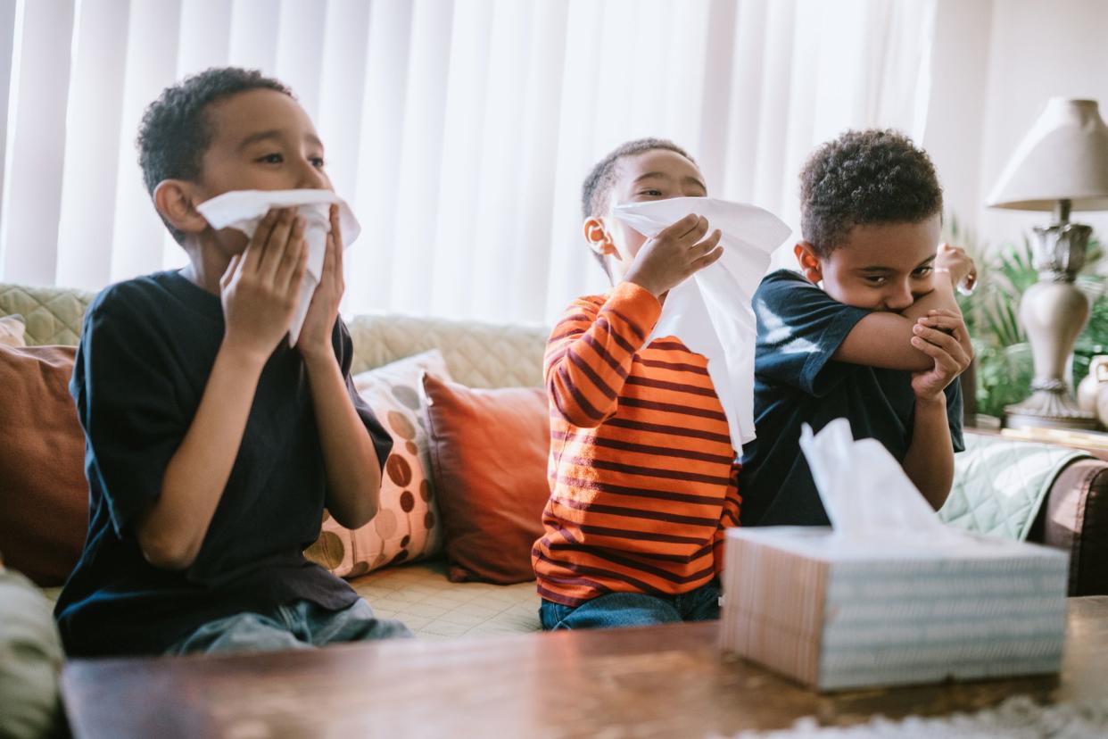 three children sneezing or coughing into tissues