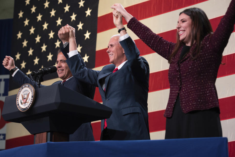 Vice President Mike Pence lifts the hands of U.S. Rep. Mike Bishop, R-Rochester, and Lena Epstein, Republican candidate in the 11th Congressional District, at a rally for Republicans in Oakland County, Monday, Oct. 29, 2018, at the Oakland County Airport in Waterford, Mich. (Tanya Moutzalias/Ann Arbor News-MLive.com via AP)