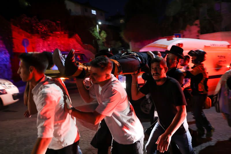 Rescue workers carry injured people outside a synagogue in Givat Zeev