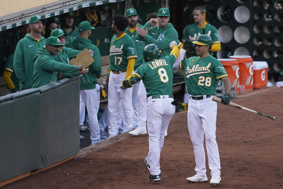 Oakland Athletics' Jed Lowrie (8) is congratulated by teammates, including Matt Olson (28), after hitting a home run against the Kansas City Royals during the fourth inning of a baseball game in Oakland, Calif., Thursday, June 10, 2021. (AP Photo/Jeff Chiu)