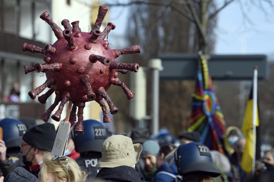 Participants stand with a Corona virus replica at a rally under the motto "Free citizens Kassel - basic rights and democracy" in Kassel, Germany, Saturday, March 20, 2021. According to police, several thousand people were on the move in the city center and disregarded the instructions of the authorities during the unregistered demonstration against Corona measures. (Swen Pfoertner/dpa via AP)