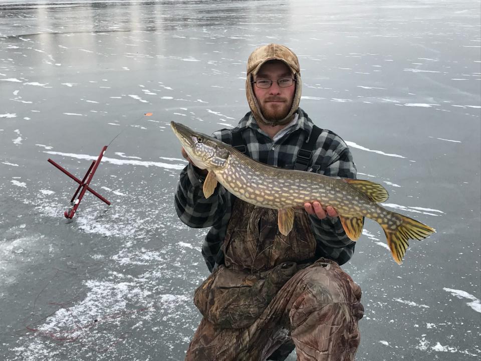 ice fisherman holding pike 