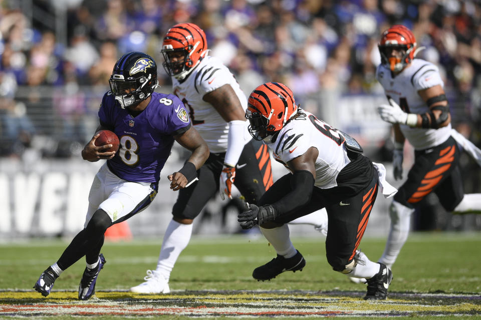 Baltimore Ravens quarterback Lamar Jackson (8) runs with the ball as Cincinnati Bengals defensive tackle Renell Wren, right, goes in for the hit during the first half of an NFL football game, Sunday, Oct. 24, 2021, in Baltimore. (AP Photo/Nick Wass)