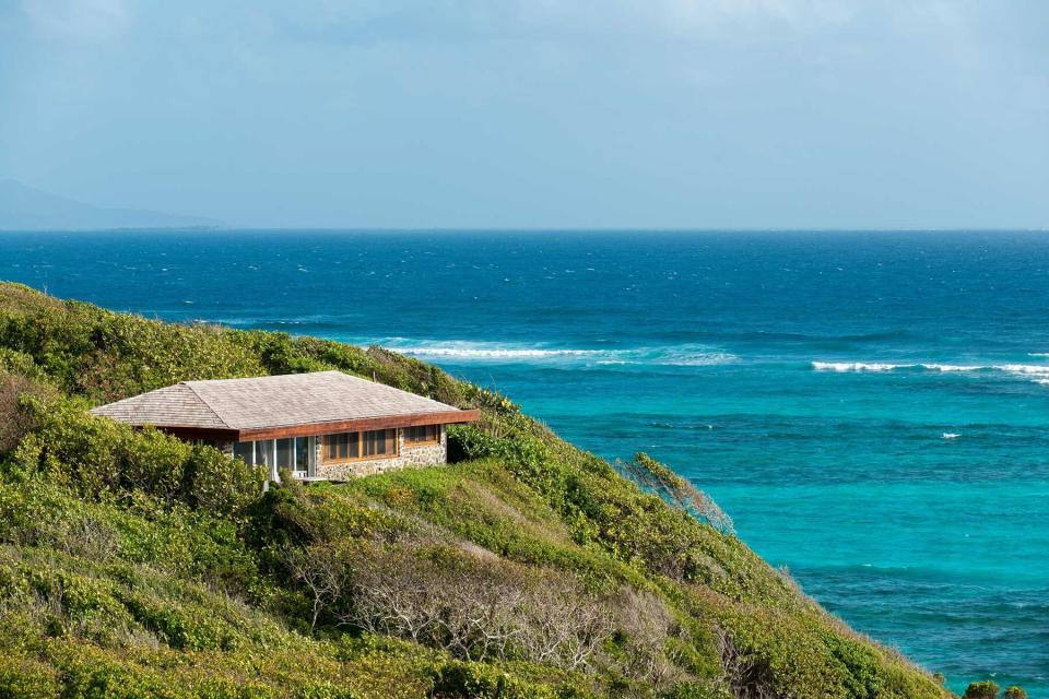 A cottage at Petit St Vincent resort sits on a hillside, with turquoise water below