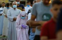 A girl attends Eid al-Adha prayers with other worshipers on the street outside Abu Hanifa mosque in Baghdad Adhamiya district, during the outbreak of the coronavirus disease (COVID-19), in Iraq, July 31, 2020. REUTERS/Thaier Al-Sudani