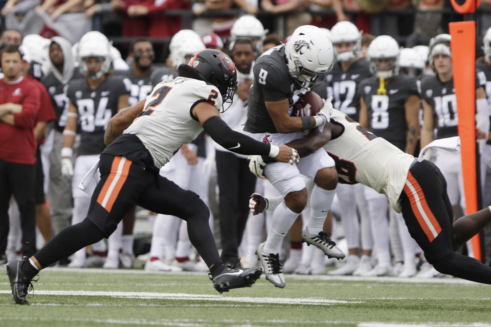 Oregon State defensive back Kitan Oladapo, right, tackles Washington State wide receiver Isaiah Hamilton (9) next to linebacker Calvin Hart Jr. (2) during the first half of an NCAA college football game, Saturday, Sept. 23, 2023, in Pullman, Wash. (AP Photo/Young Kwak)