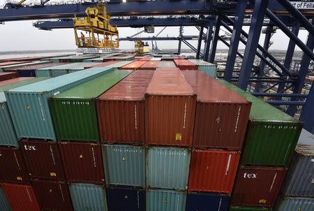 Port workers inspect containers before they are unloaded as the largest container ship in world, CSCL Globe, docks during its maiden voyage, at the port of Felixstowe in south east England, January 7, 2015. REUTERS/Toby Melville