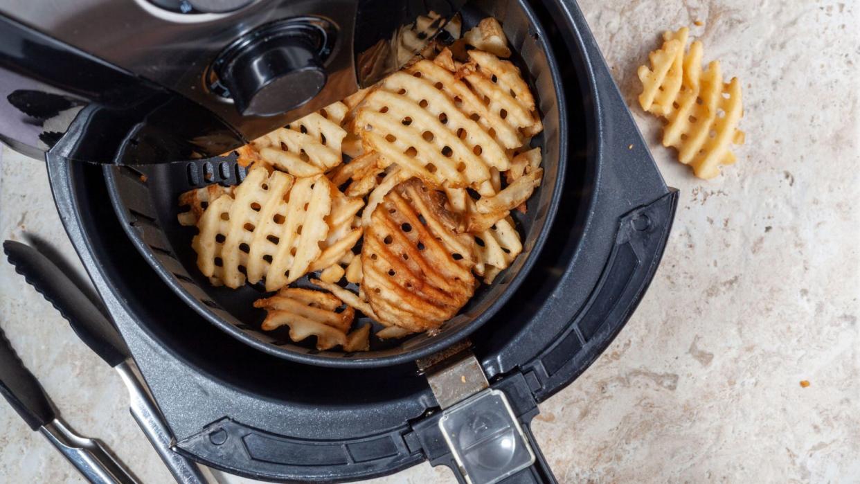  An open air fryer with waffle fries inside 