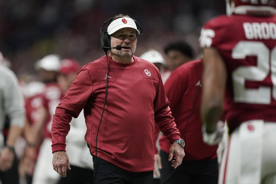 Oklahoma interim head coach Bob Stoops, right, waits to greet running back Kennedy Brooks (26), who had scored a touchdown against Oregon during the first half of the Alamo Bowl NCAA college football game, Wednesday, Dec. 29, 2021, in San Antonio. (AP Photo/Eric Gay)