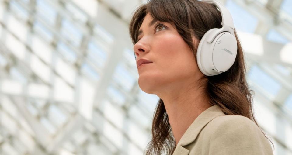 white woman with brown hair wearing white Bose headphones 