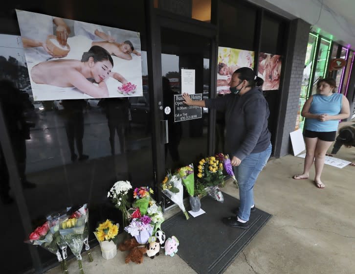 Jessica Lang pauses and places her hand on the door in a moment of grief after dropping off flowers with her daughter Summer at Youngs Asian Massage parlor where four people were killed, Wednesday, March 17, 2021, in Acworth, Ga. At least eight people were found dead at three different spas in the Atlanta area Tuesday by suspected shooter Robert Aaron Long. Lang, a local resident who lives nearby, said she knew one of the victims. (Curtis Compton/Atlanta Journal-Constitution via AP)