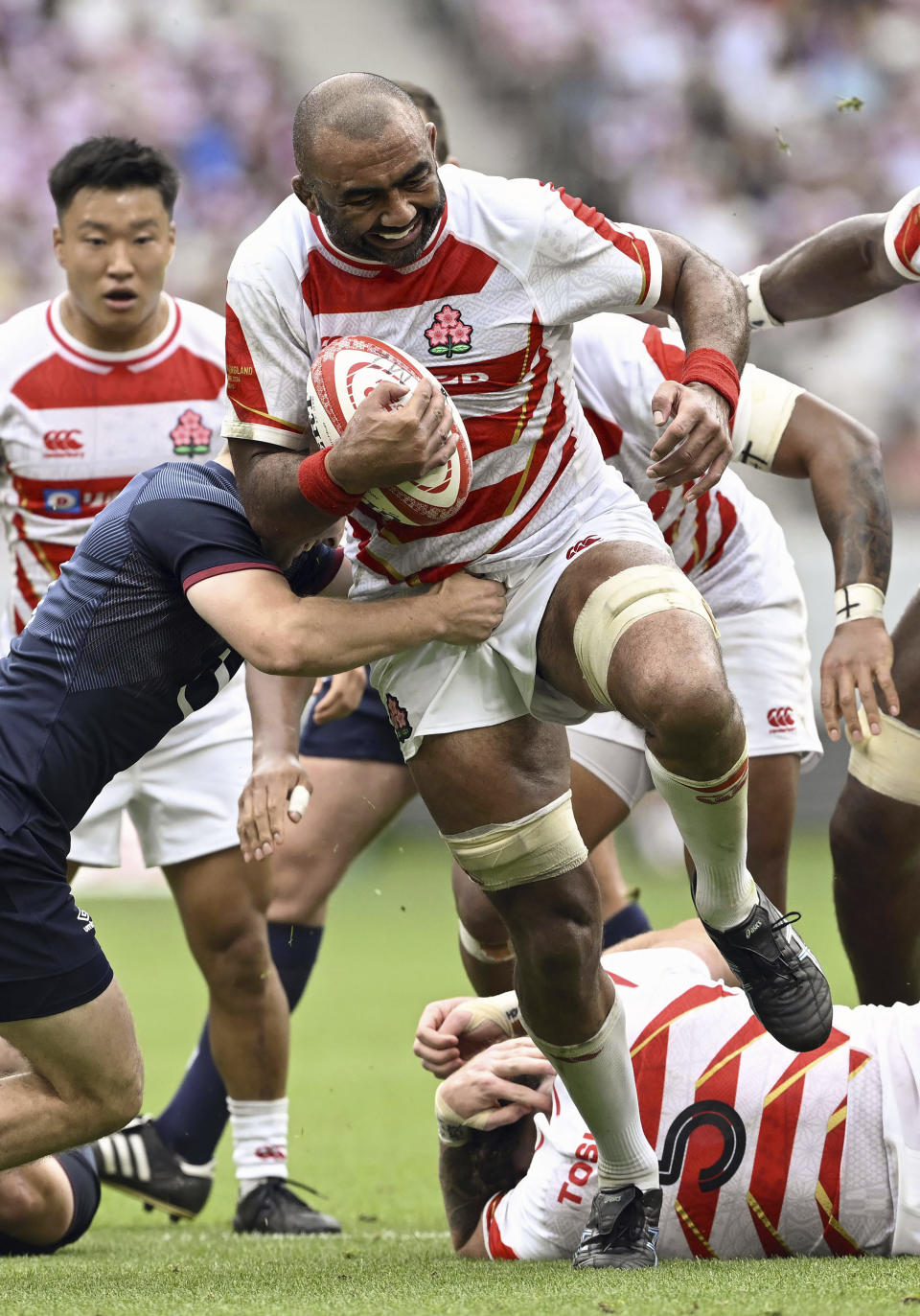 Japan’s Michael Leitch runs with the ball against England’s defense in the last half of a rugby test match in Tokyo, Japan, Saturday, June 22, 2024. England's stop in Tokyo on its way to a two-test rugby tour of New Zealand was no contest as the visitors beat Japan 52-17 Saturday in an eight-try performance at the National Stadium in Tokyo. (Kyodo News via AP)