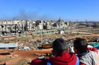 Syrian children watch as buses depart during an evacuation operation of rebel fighters and civilians from rebel-held neighbourhoods of Aleppo on December 15, 2016