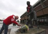 Serge Laflamme, lights a candle at the statue of Jean Beliveau outside the arena named after Beliveau in Longueuil, Quebec December 3, 2014. REUTERS/Christinne Muschi