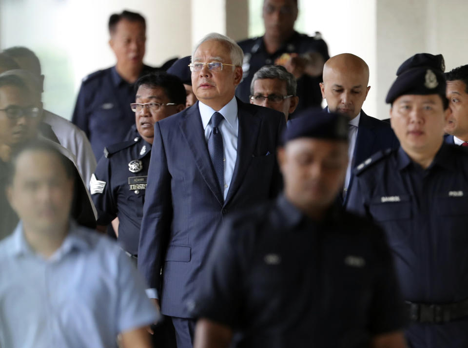 FILE - In this Oct. 4, 2018, file photo, former Malaysian Prime Minister Najib Razak, center, walks out of courtroom at Kuala Lumpur High Court in Kuala Lumpur, Malaysia. Najib is hardly lying low ahead of his corruption trial set to begin Tuesday, Feb. 12, 2019, on charges related to the multibillion-dollar looting of the 1MDB state investment fund. He’s crooned about slander in an R&B video and vilified the current government on social media to counter portrayals of him as corrupt and out of touch. Najib denies wrongdoing and his lawyers are seeking delay.(AP Photo/Vincent Thian, File)