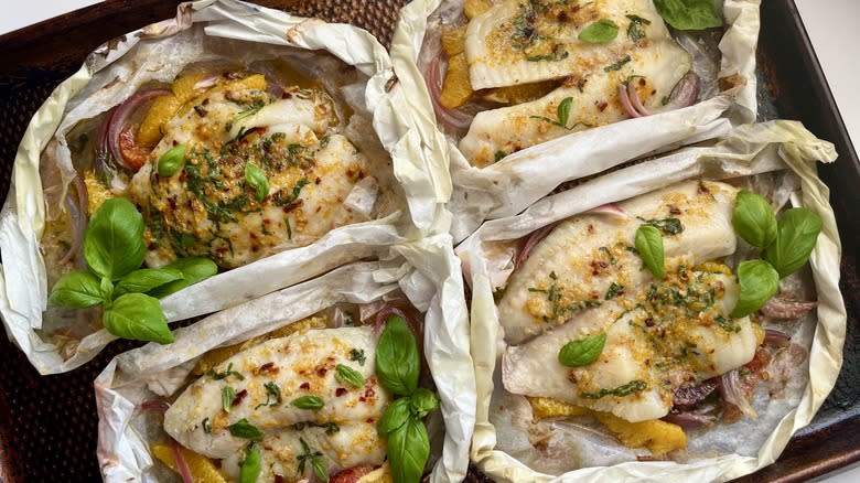 four tilapia fish fillets baked in parchment papillote on baking dish