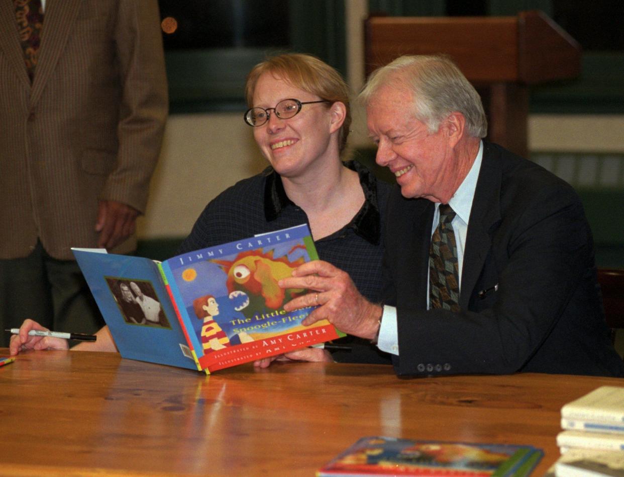 Former President Jimmy Carter and his daughter, Amy, look over their new children's book, "The Little Baby Snoogle-Fleejer," before a book-signing on Dec. 13, 1995, at a bookstore in New York. The story is based on a tale Carter would tell his children when they were young.
