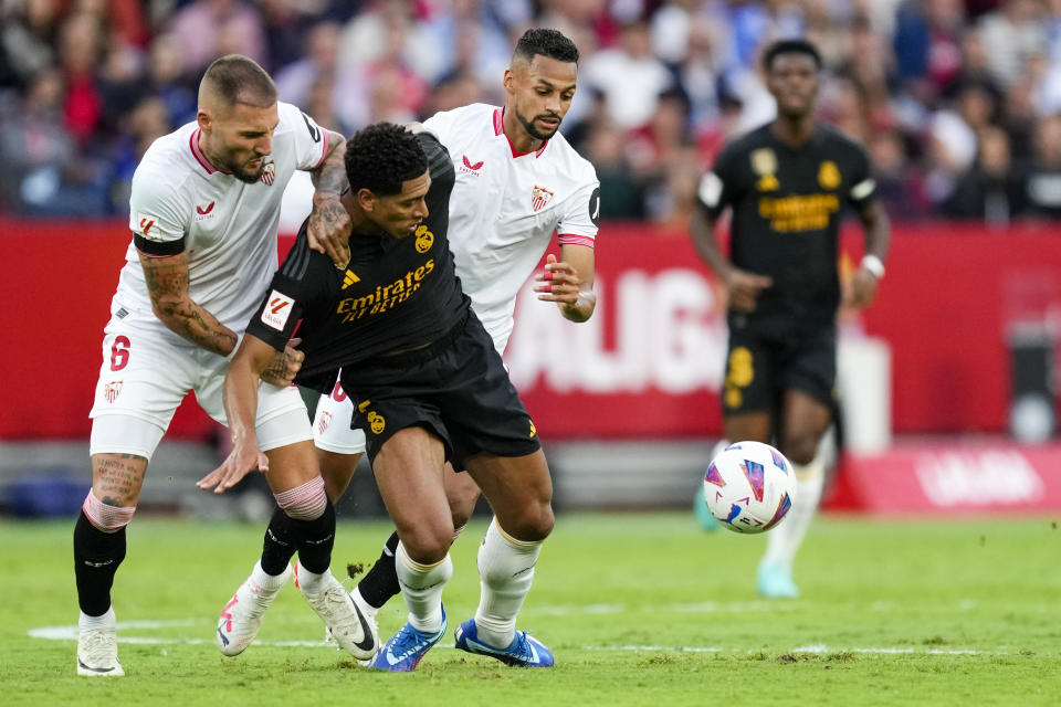 Sevilla's Nemanja Gudelj, left, duels for the ball with Real Madrid's Jude Bellingham during a Spanish La Liga soccer match between Sevilla and Real Madrid, at the Ramon Sanchez Pizjuan stadium in Seville, Spain, Saturday, Oct. 21, 2023. (AP Photo/Jose Breton)