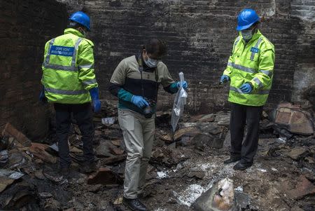 Members of the crime scene investigation unit collect evidence from a possible arson attack at a shoe factory that burned down in Lahore January 14, 2015. REUTERS/Zohra Bensemra