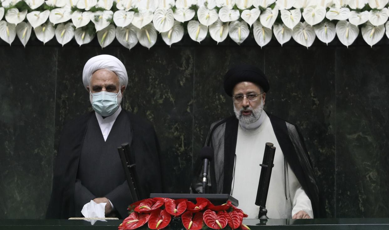 President Ebrahim Raisi, right, takes his oath as president, as Judiciary Chief Gholamhossein Mohseni Ejehi listens in a ceremony at the parliament.