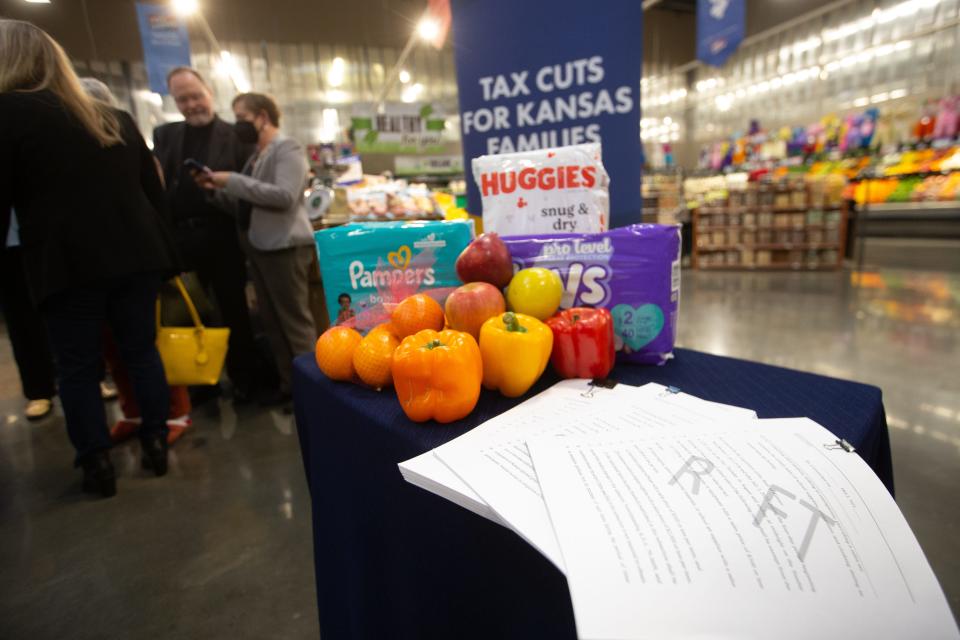 The three proposed bills offered by Laura Kelly that would cut sales taxes are used as props along with grocery items and diapers during a news conference Monday in Roeland Park's Price Chopper.