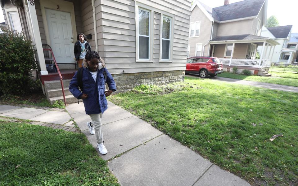 Adrian Burrows, 10, a fifth grader at School 52, heads for the bus with his mother, Adriana Jackson watching from in front of their home on Grand Avenue. The bus is often late making him also late to school.