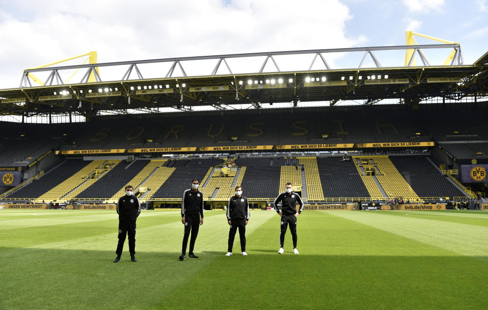 Referee Deniz Aytekin, 2nd left, and his team stand on the pitch before the German Bundesliga soccer match between Borussia Dortmund and Schalke 04 in Dortmund, Germany, Saturday, May 16, 2020. The German Bundesliga becomes the world's first major soccer league to resume after a two-month suspension because of the coronavirus pandemic. (AP Photo/Martin Meissner, Pool)