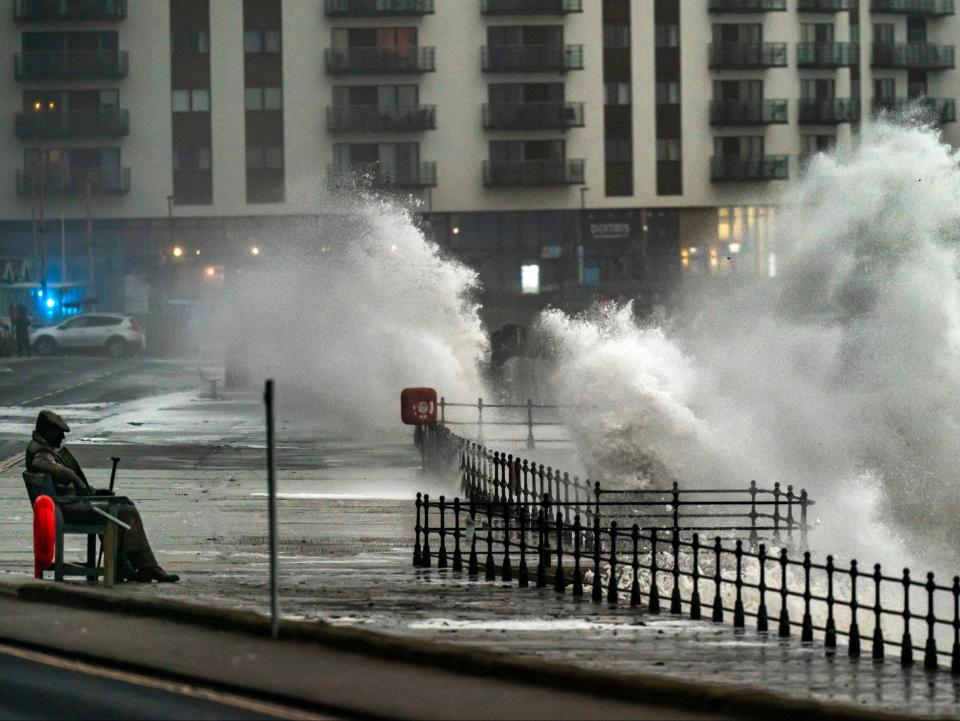 Waves crash near to the 'Freddie Gilroy' sculpture by artist Ray Lonsdale in Scarborough, as Storm Babet batters the country (PA)