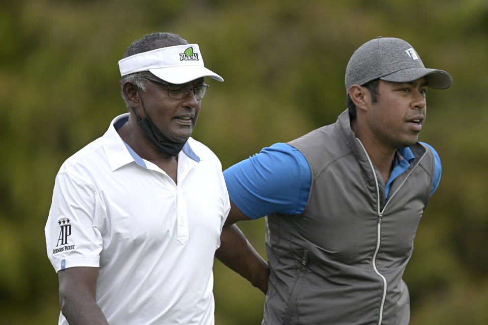 Vijay Singh, left, and his son Qass walk on the 18th fairway after hitting their tee shots during the first round of the PNC Championship golf tournament, Saturday, Dec. 19, 2020, in Orlando, Fla. (AP Photo/Phelan M. Ebenhack)